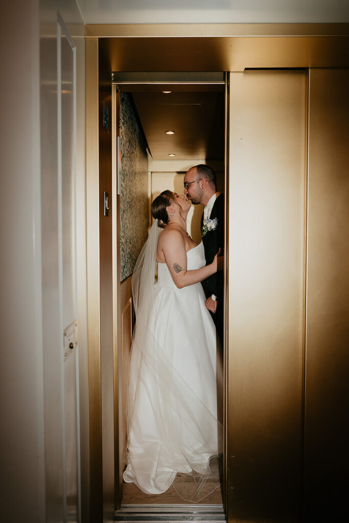 the bride and groom kissing in a hallway. 