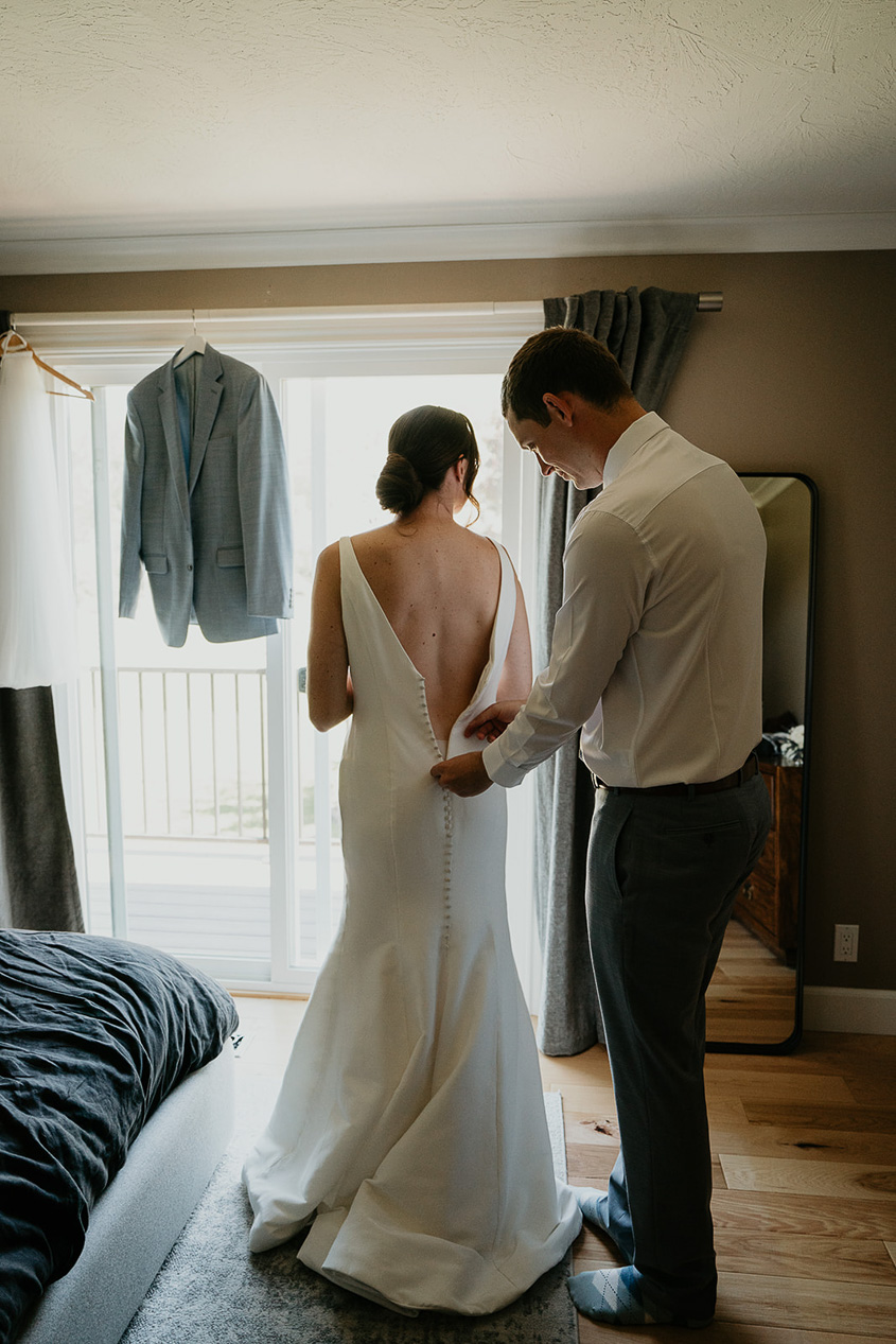 the groom zipping up the bride's dress. 