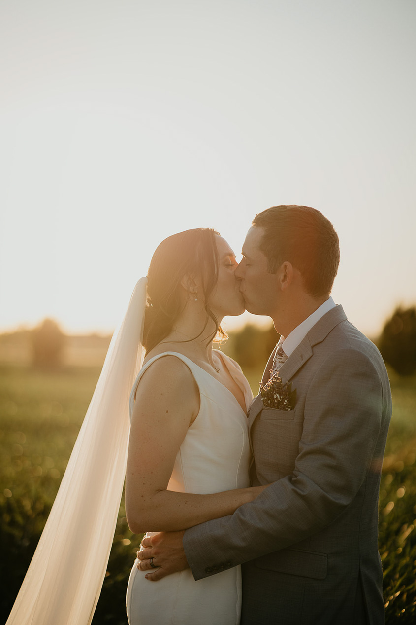 The newlyweds kissing with the sunset in the background at Dusted Valley.