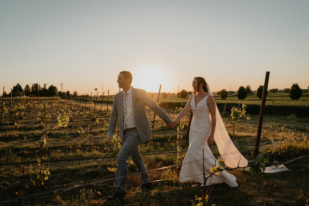 the newlyweds walking through a farm field. 