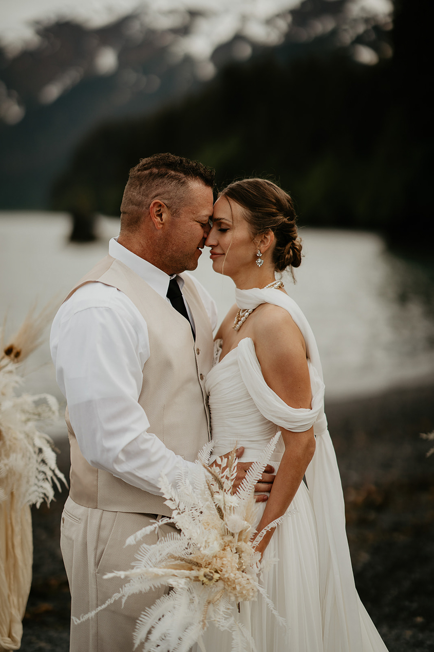 A couple embracing each other on the beach during while they elope in Alaska.