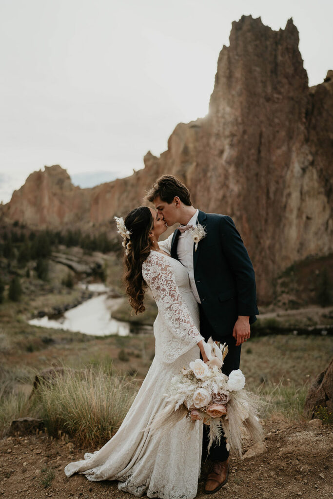 A couple kissing with a river and cliffs in the background. 