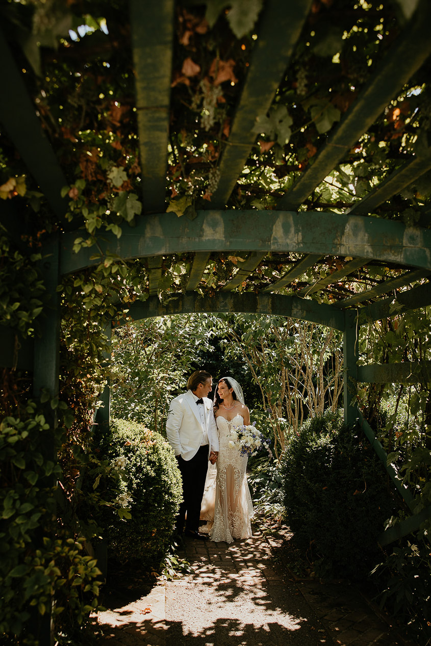 the bride and groom holding hands under a pergola at Deepwood Museum and Gardens.