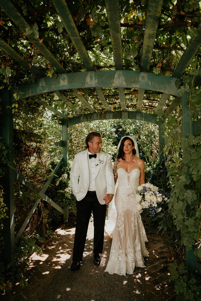 the bride and groom holding hands under a pergola at Deepwood Museum and Gardens.