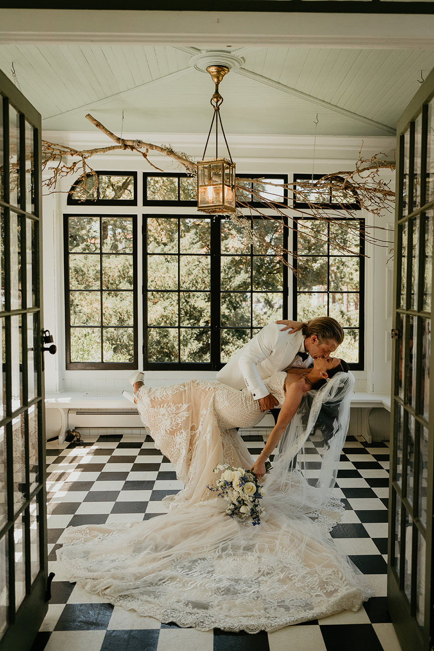 the bride and groom kissing in a sun room. 