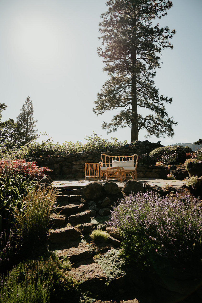 An outdoor bench and chair in a garden. 