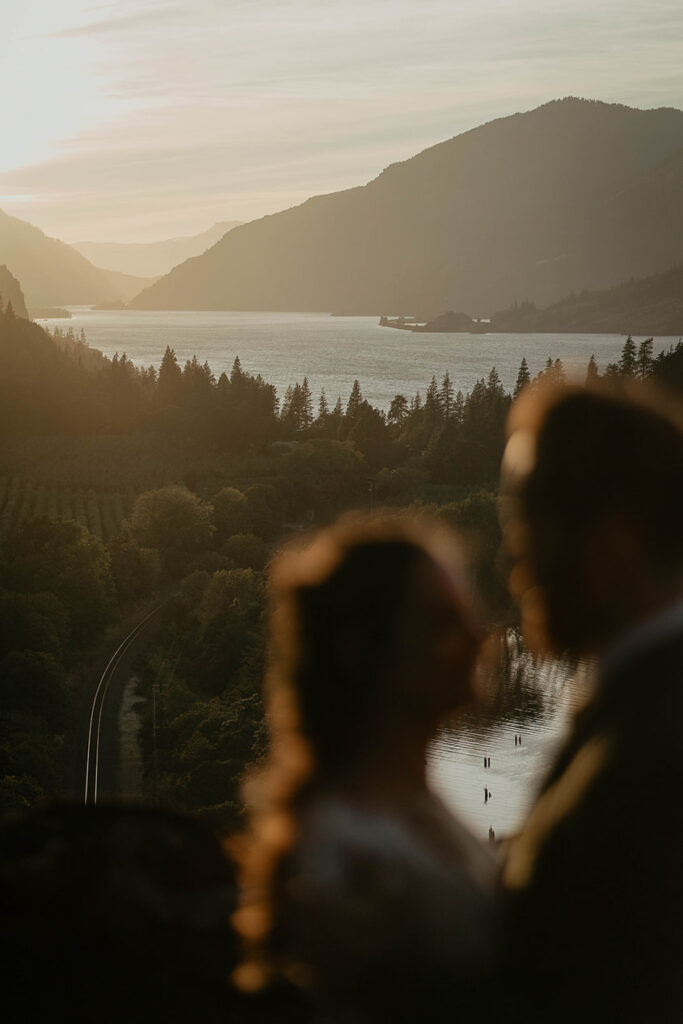 A couple holding each other close at The Griffin House with the Columbia River Gorge in the background. 