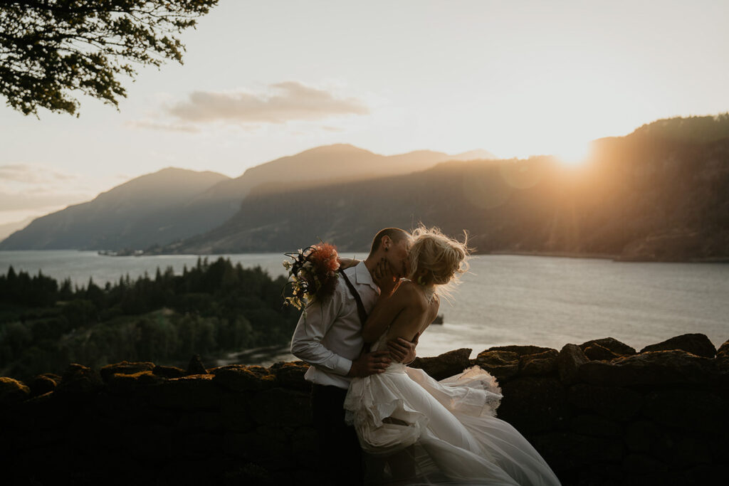 A couple kissing with the Columbia River Gorge in the background. 