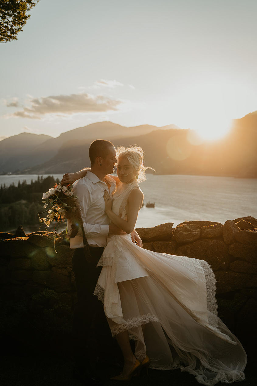 A couple hugging with the Columbia River Gorge behind them.