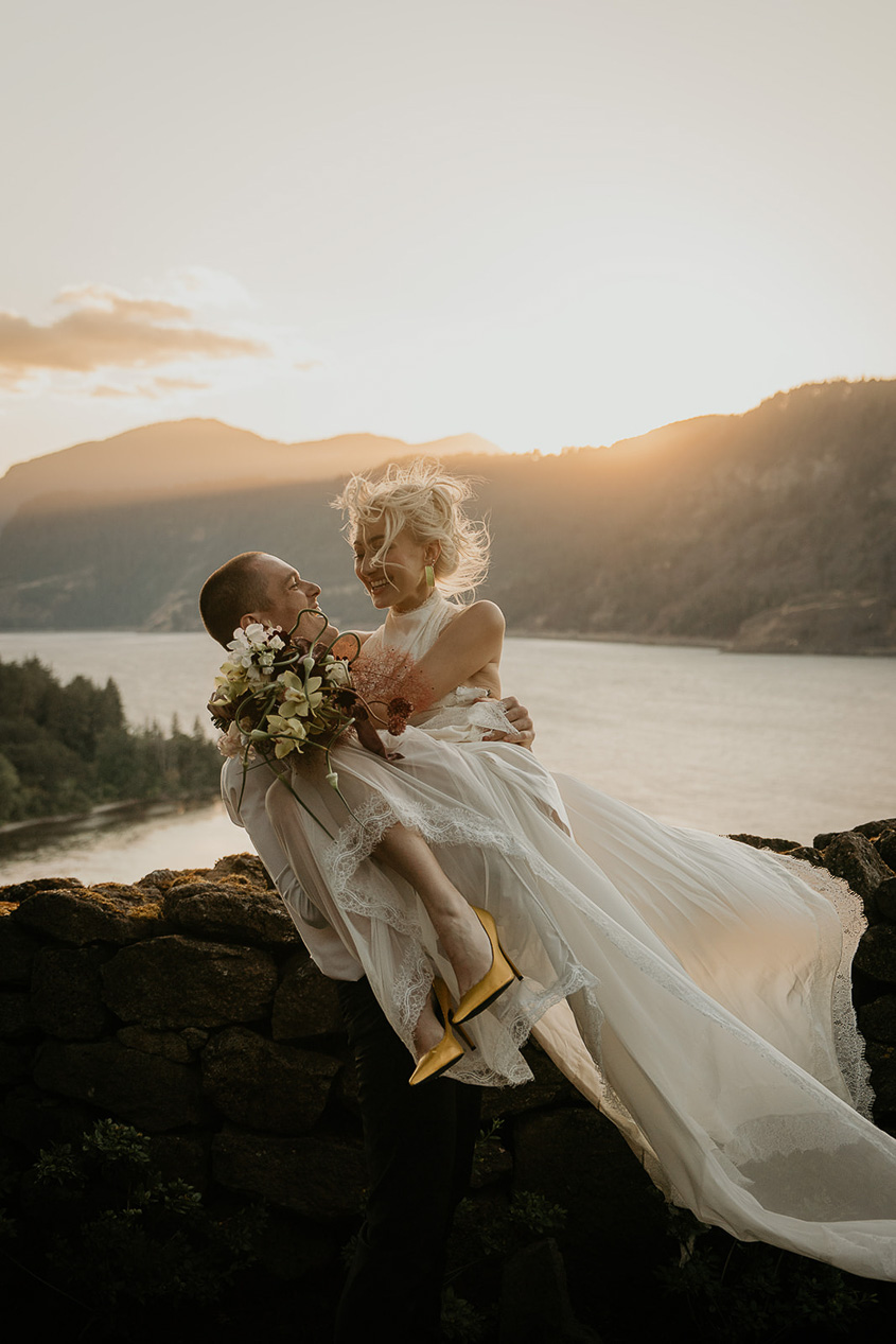 A couple hugging and laughing with the Columbia River Gorge in the background. 