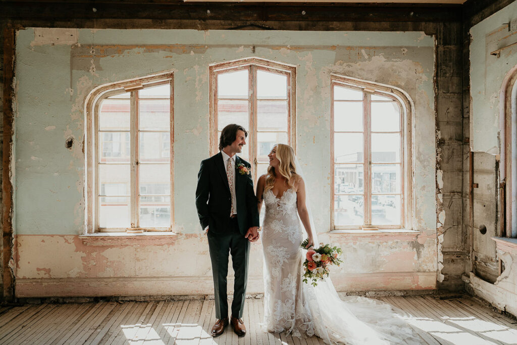 The bride and groom standing in room holding hands at The Ruins at the Astor. 