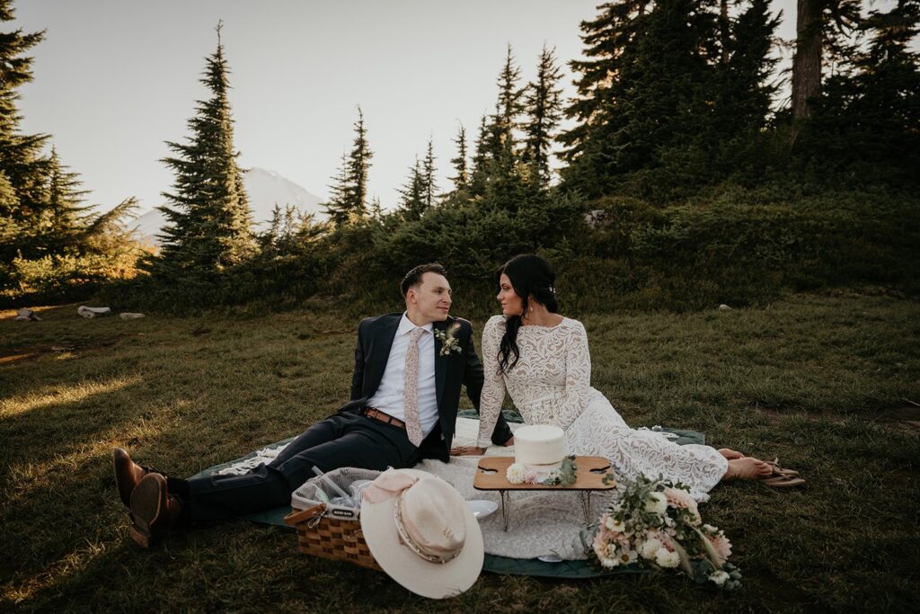 Bride and groom sit on the ground during their elopement picnic at North Cascades National Park