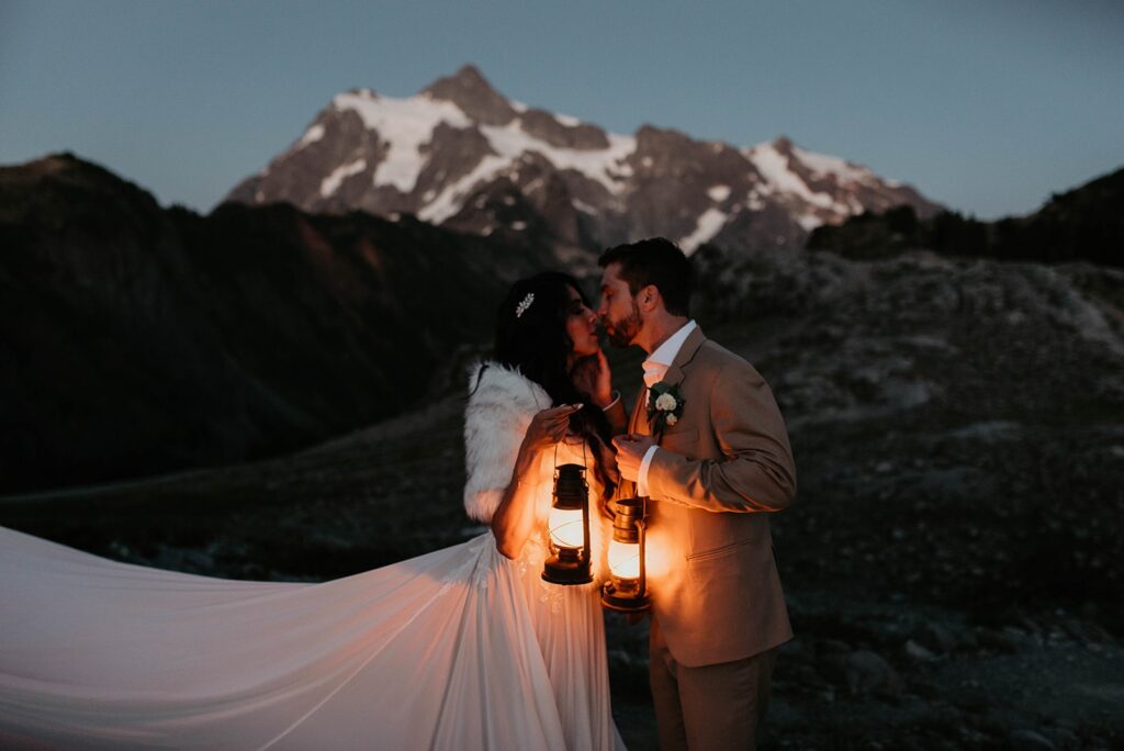 Bride and groom kiss while holding lanterns during their North Cascades elopement 