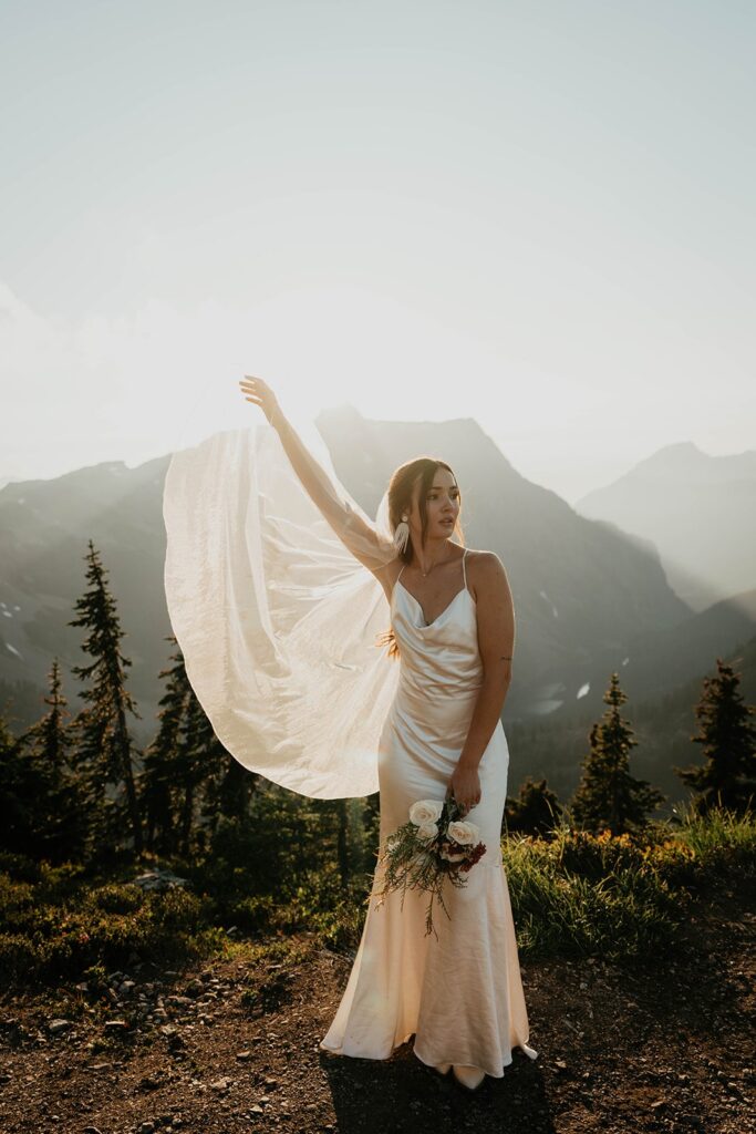 Bride lifts her white veil in the air during adventure photos at her North Cascades National Park elopement 