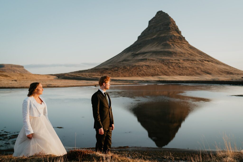 Bride and groom stand by the lake at Kirkjufell during their elopement in Iceland 