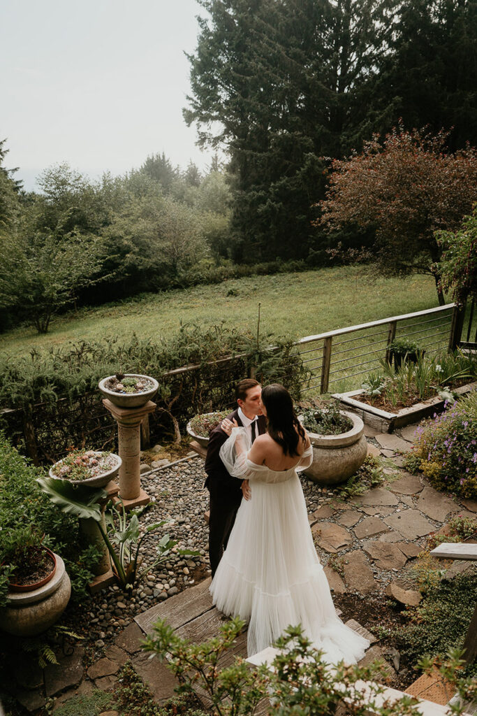 A couple kissing on the back porch of a pacific northwest home. 