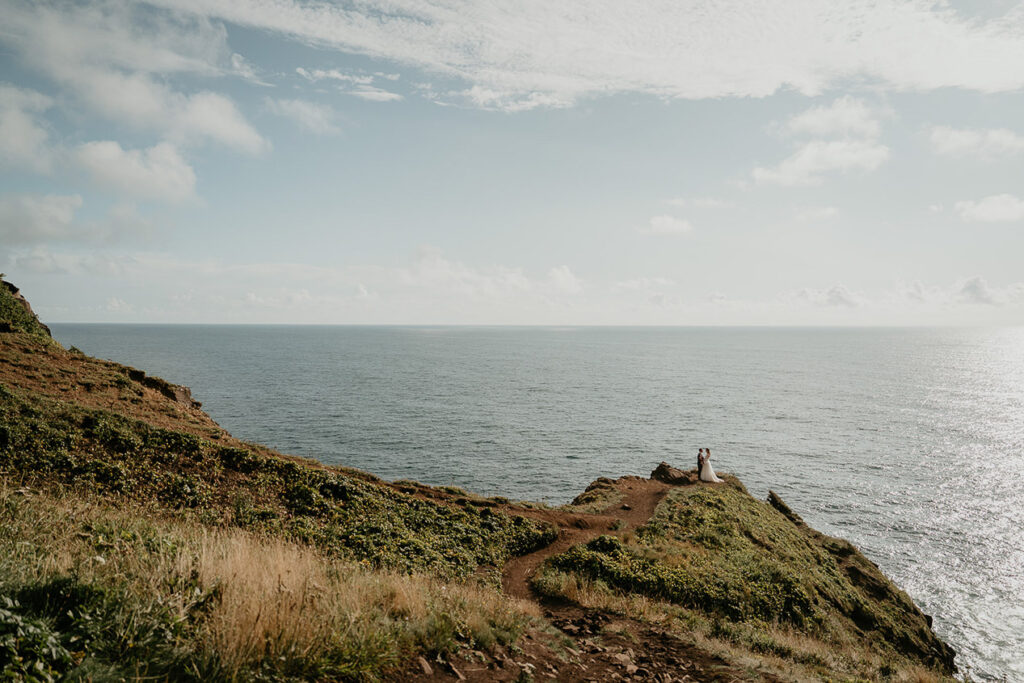 the newlyweds holding each on the cliffside during their Oregon Coast elopement. 