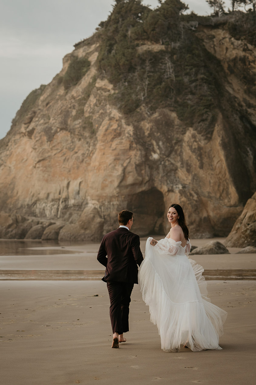 the newlyweds walking barefoot on the beach during their Oregon Coast elopement. 