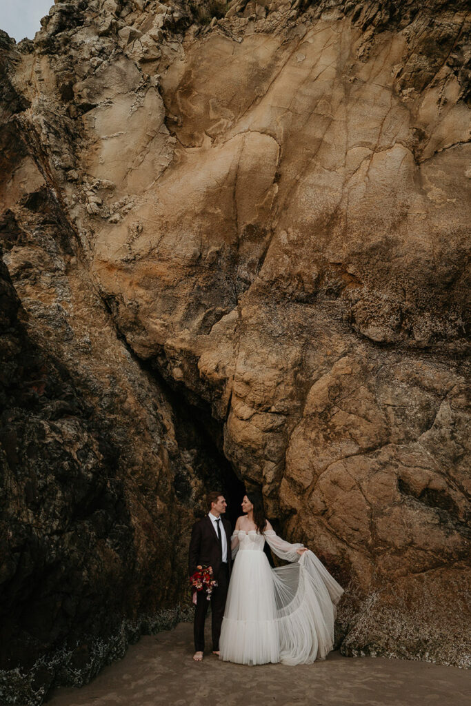 The newlyweds standing next to a cliffside. 