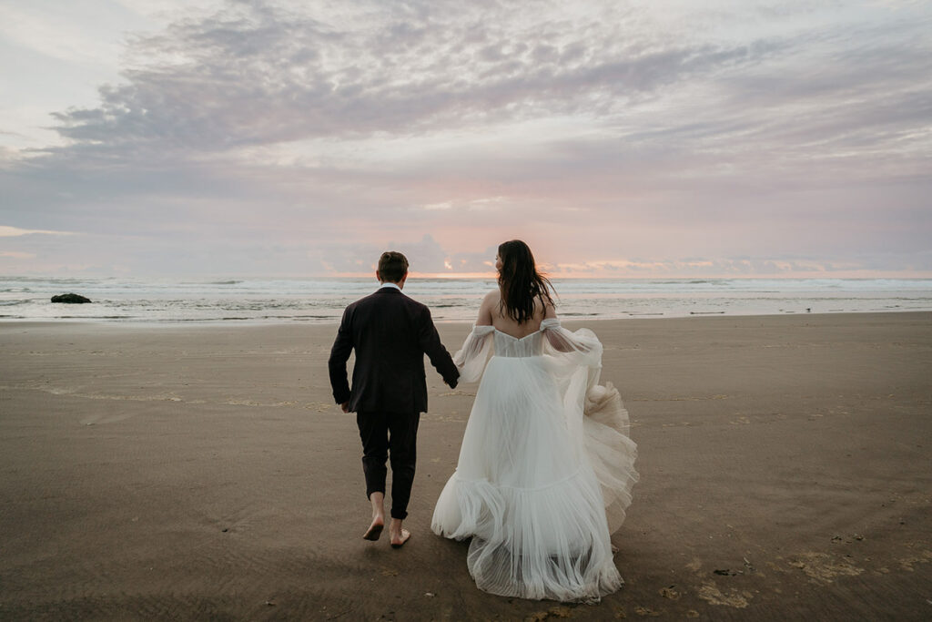 the newlyweds walking barefoot on the beach. 