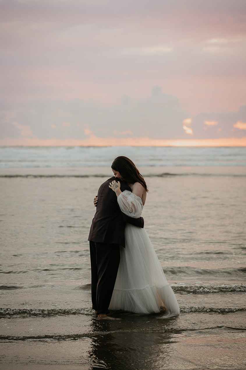 the newlyweds holding each other in the ocean during their Oregon Coast Elopement. 